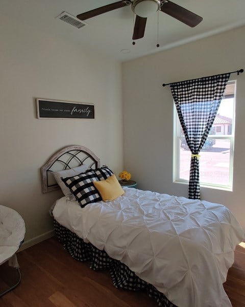 a bedroom with a bed and a window and a ceiling fan