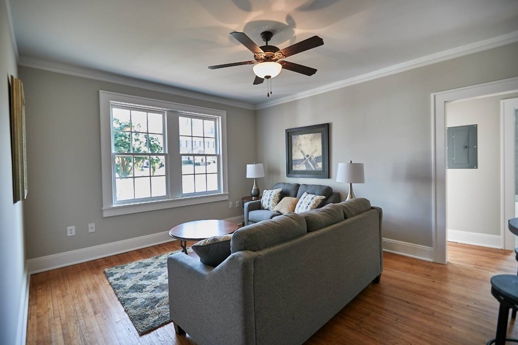 A living room with a grey couch and a ceiling fan.