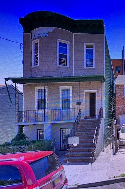 A red car is parked in front of a two-story building.