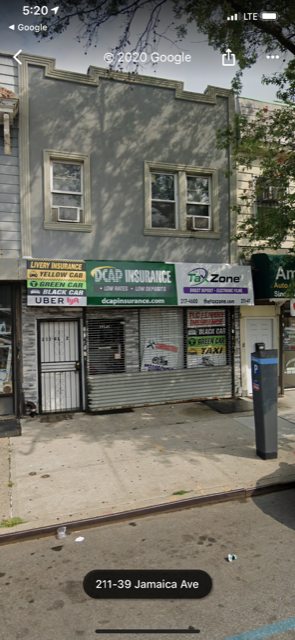 A street view of a building with a closed shutter and a sign that reads "211-39 Jamaica Ave".