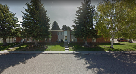 A street view of a residential area with houses and trees.