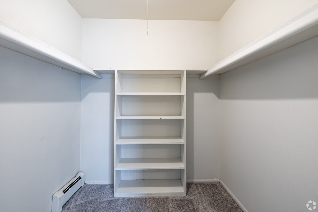 a walk in closet with empty shelves and a white wall