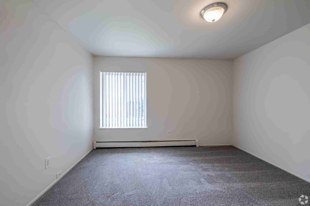 an empty room with a window and white walls