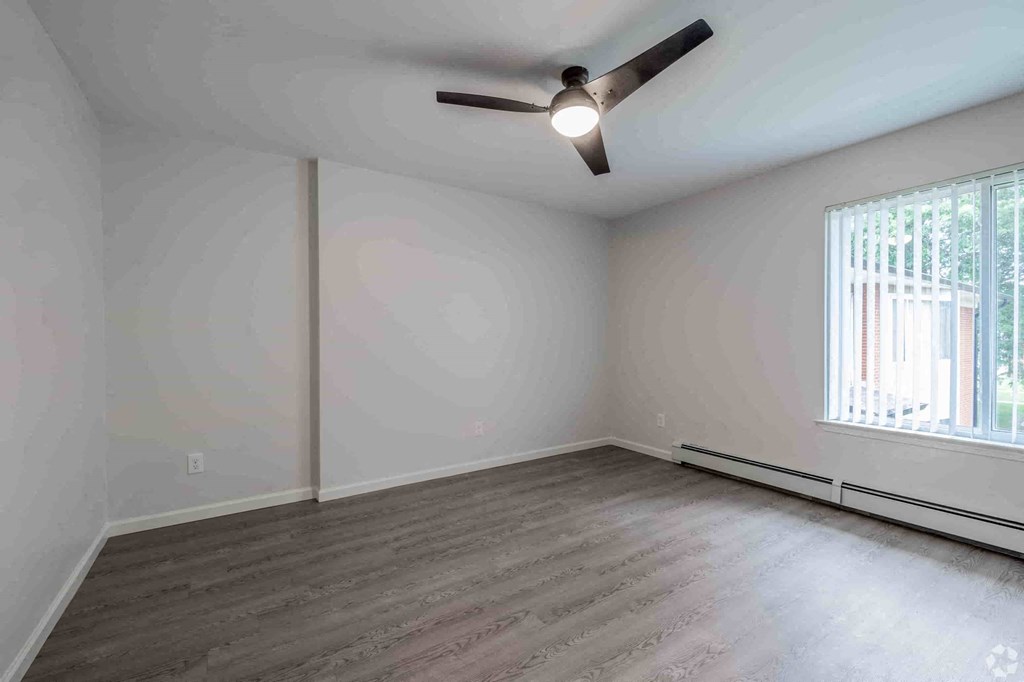 an empty living room with white walls and a ceiling fan