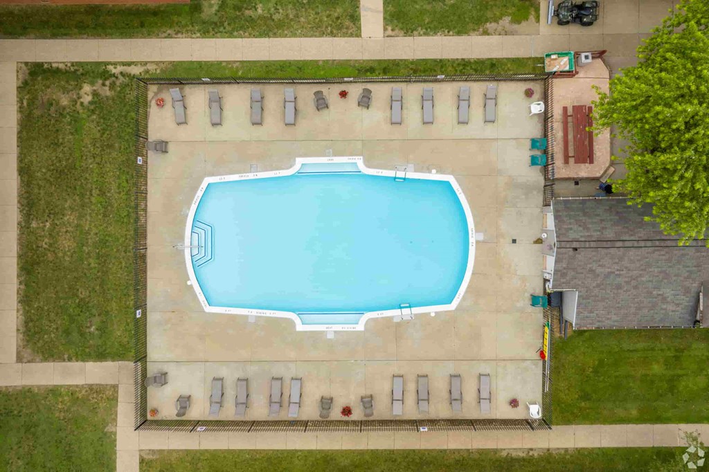 arial view of a swimming pool in the middle of a lawn and a building