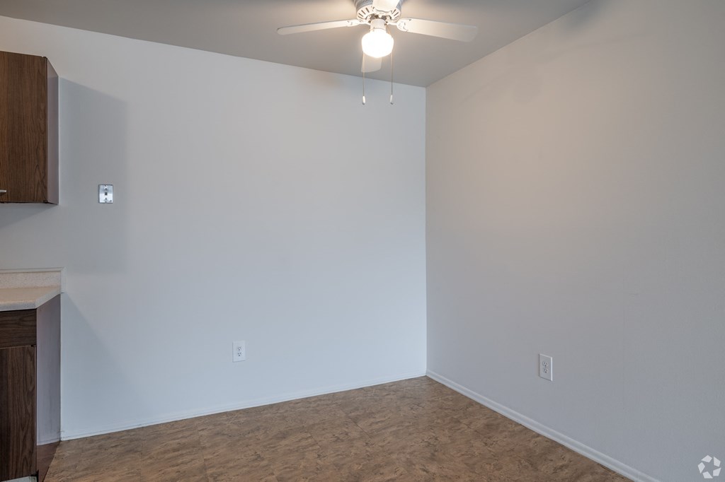 an empty living room with white walls and a ceiling fan
