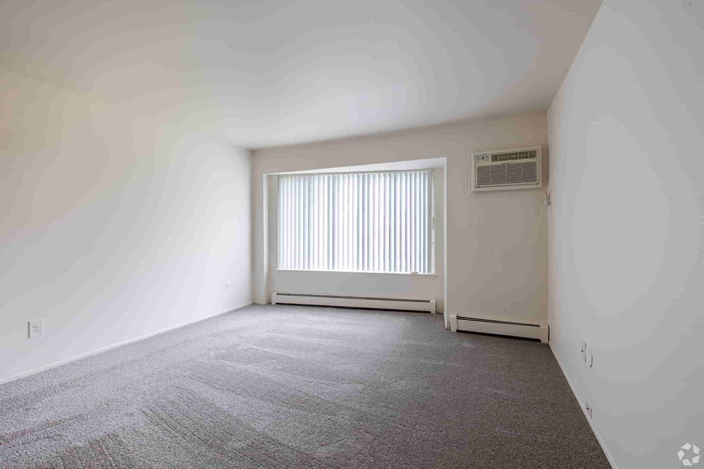 an empty living room with a window and white walls