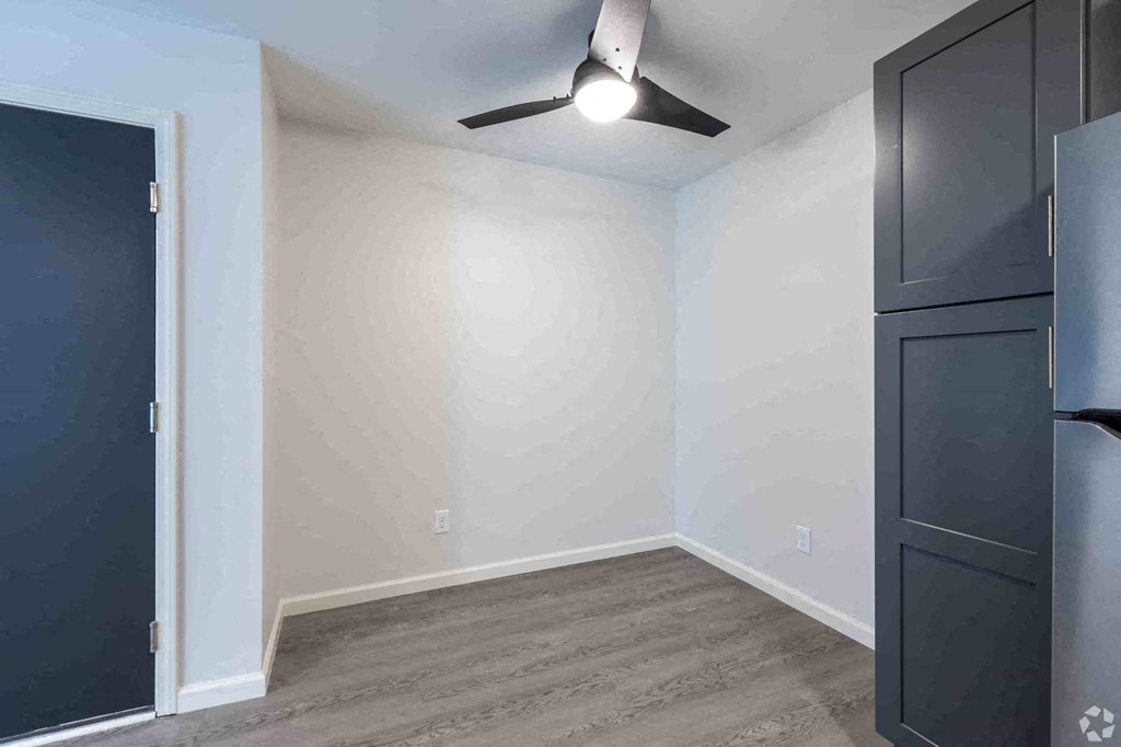 a bedroom with white walls and a black closet and a ceiling fan