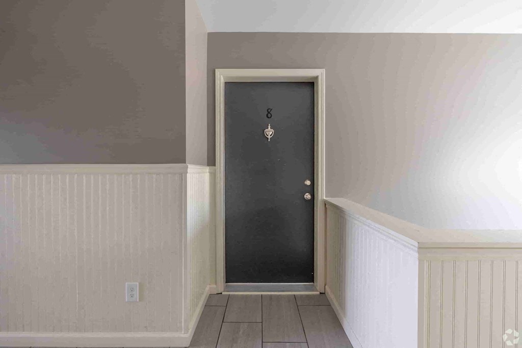 a black door in a room with white walls and a wooden floor