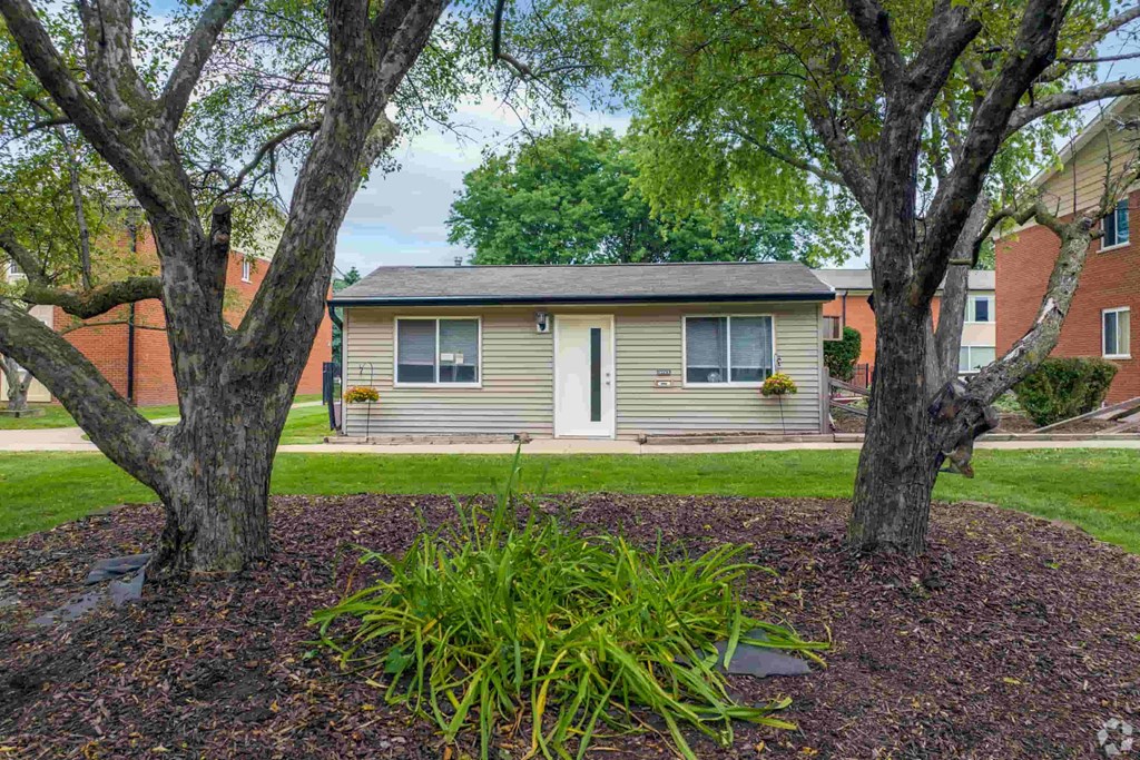 a small yellow house with trees in front of it
