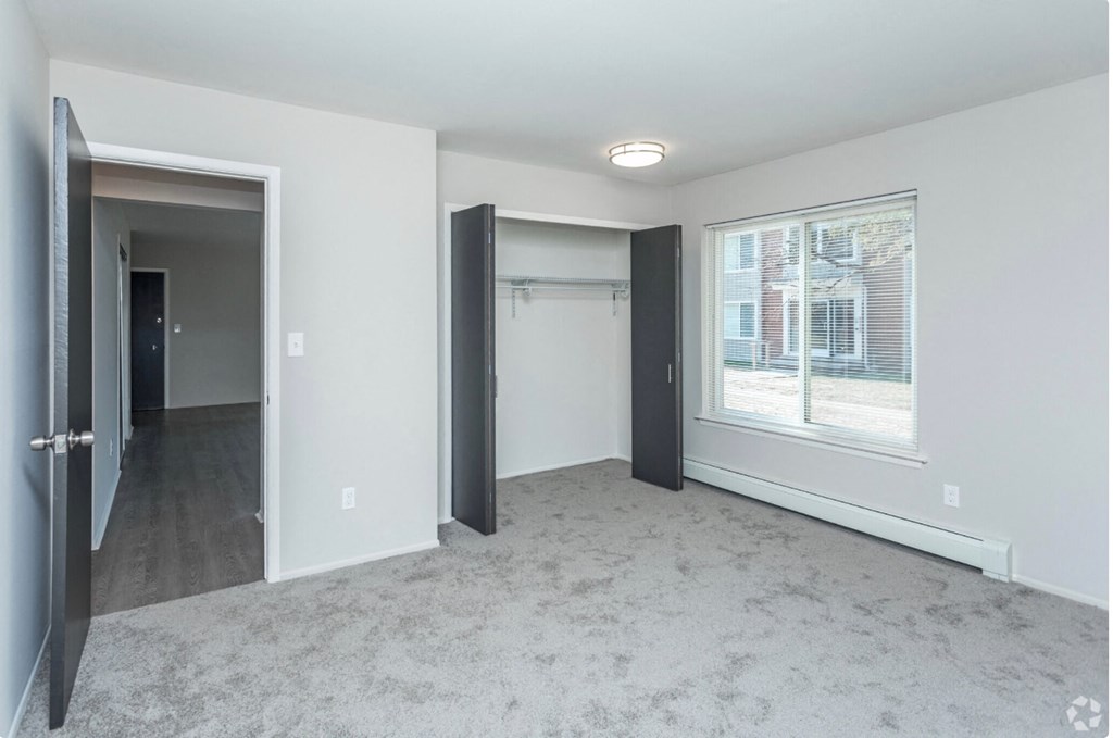 an empty living room with a large window and a closet