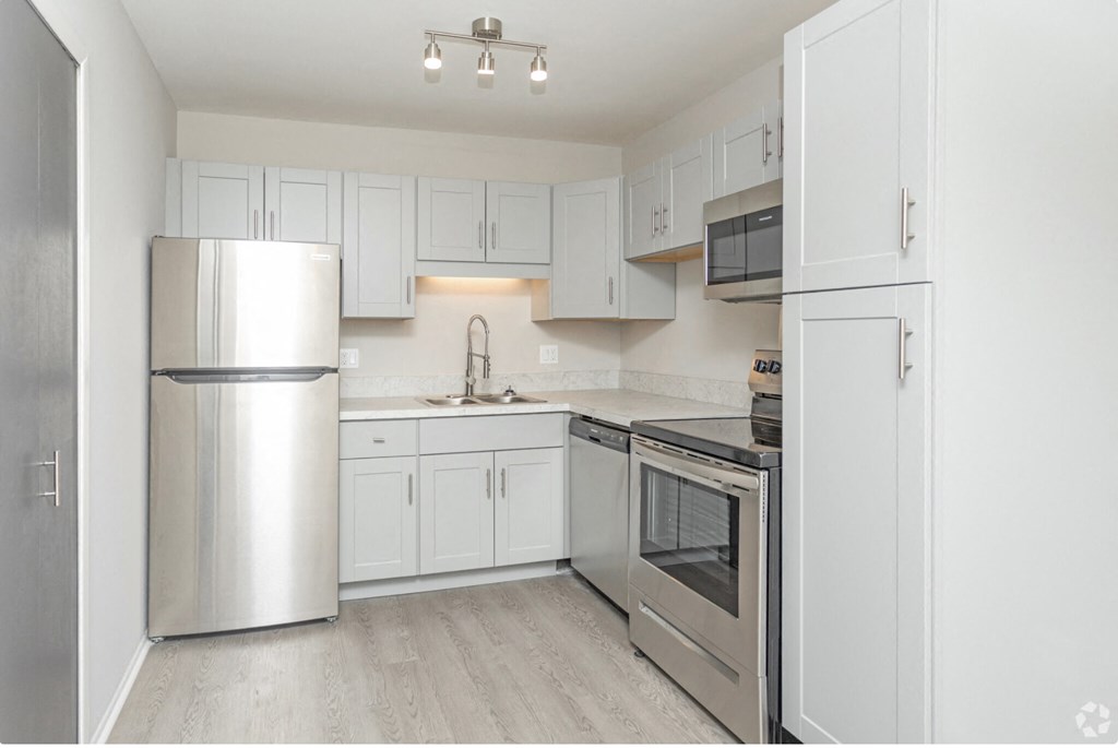 a white kitchen with stainless steel appliances and white cabinets