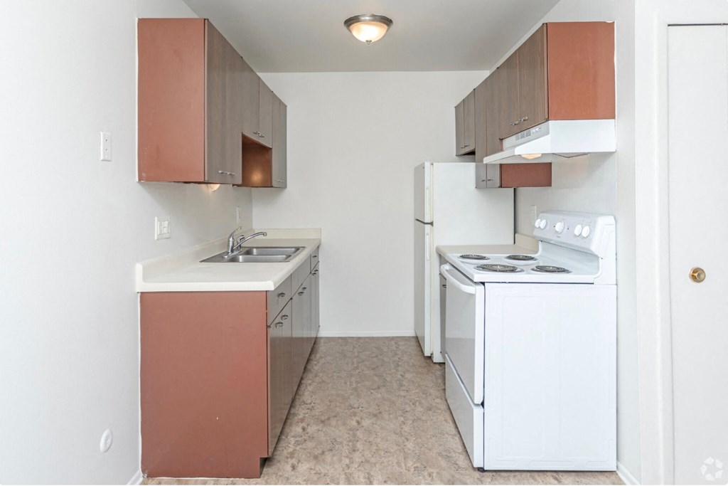 an empty kitchen with white appliances and brown cabinets