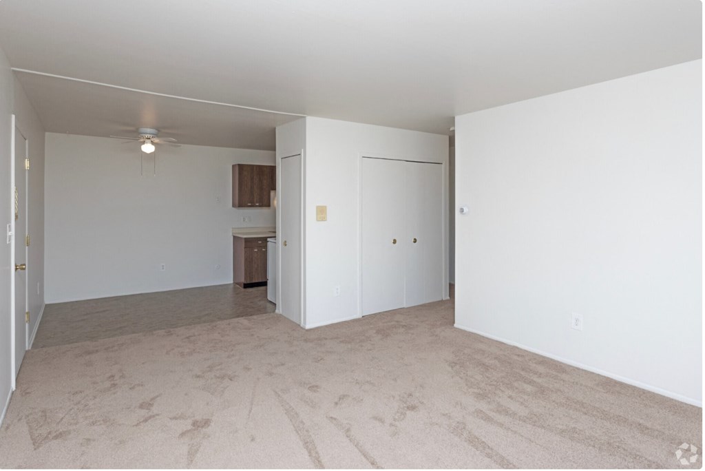 an empty living room with a ceiling fan and white walls