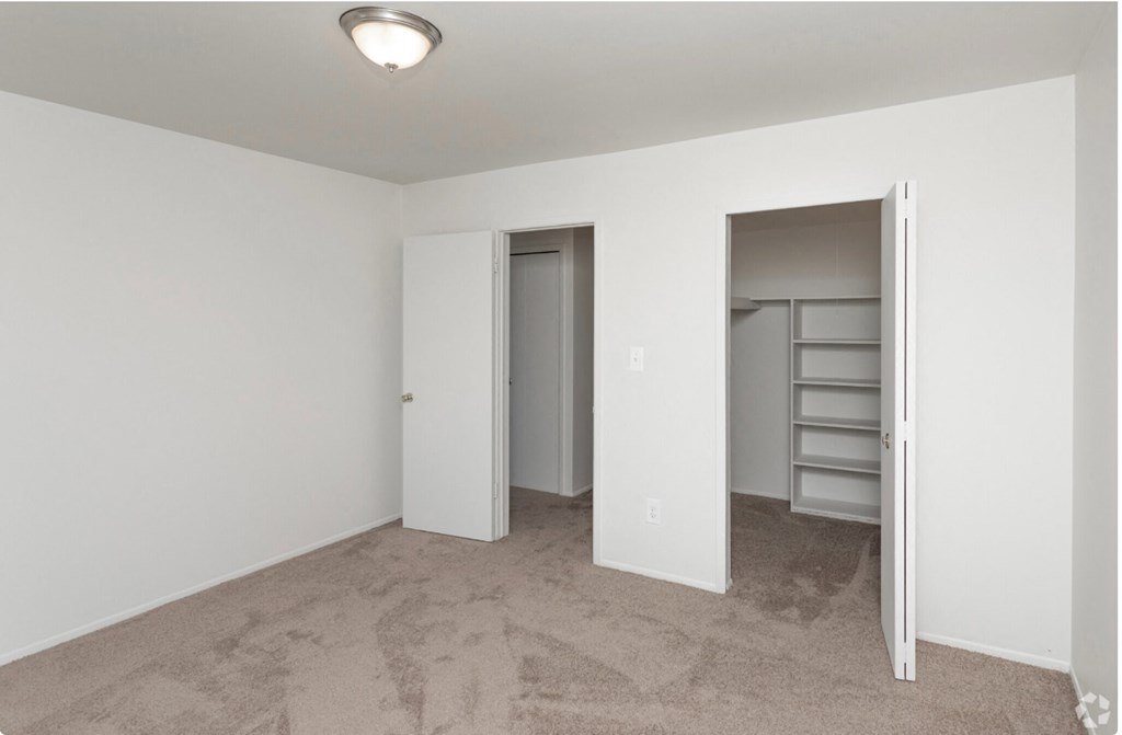 an empty bedroom with a closet and a door to the bathroom