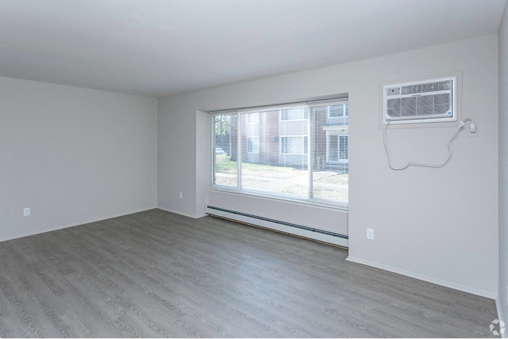 an empty living room with a window and a air conditioner