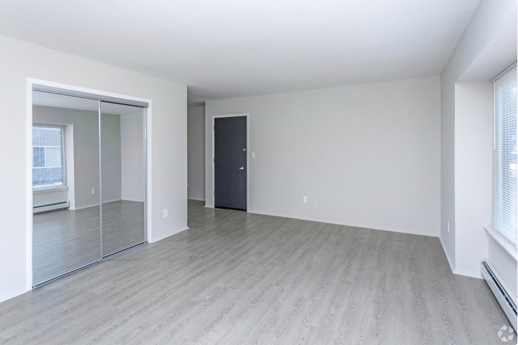 the living room and dining room of an empty apartment with white walls and wood floors