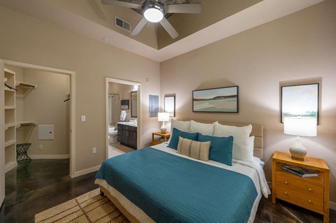 A bedroom with a bed, nightstand, and a painting on the wall.