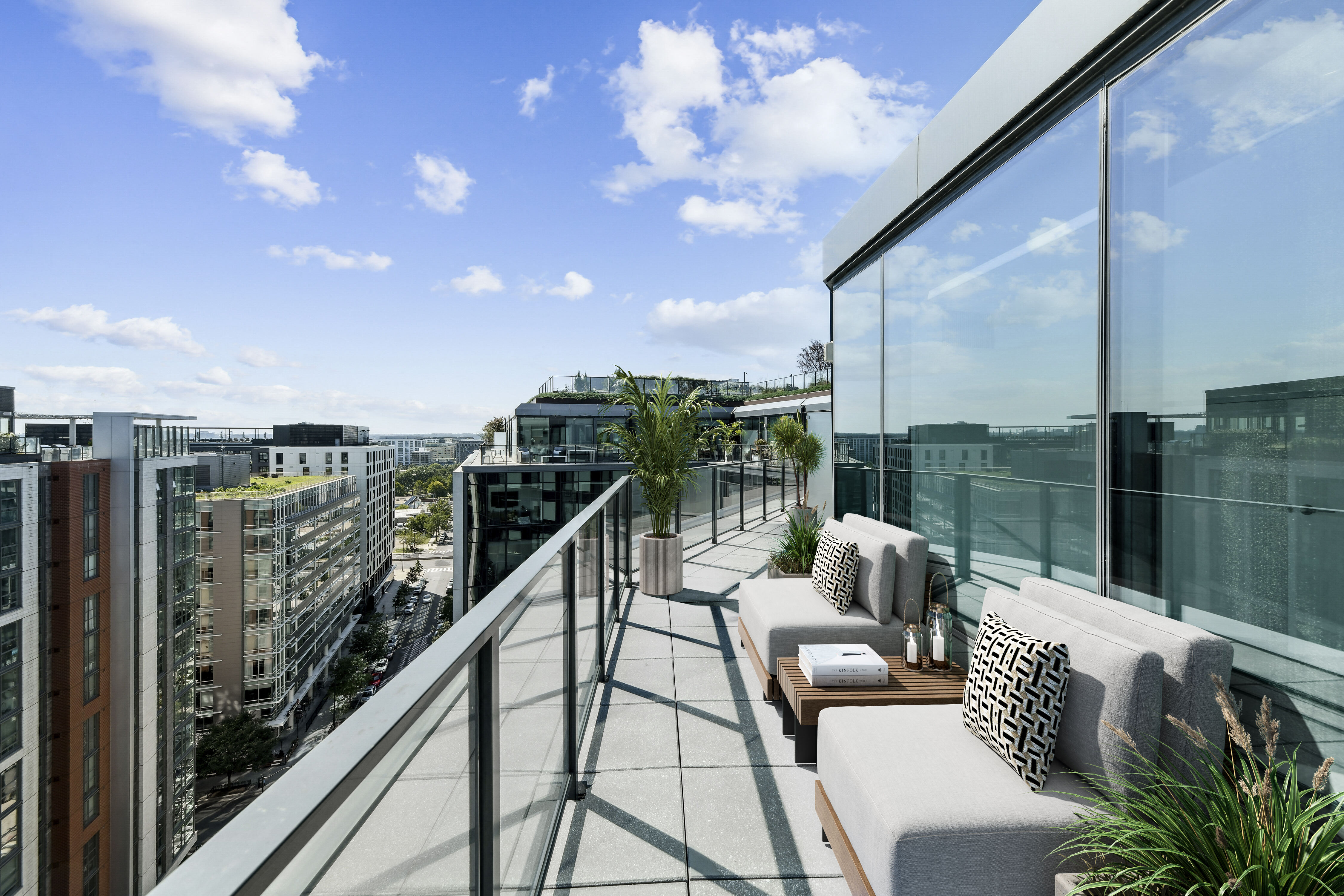 Large balcony terrace with glass railing and lounge seating