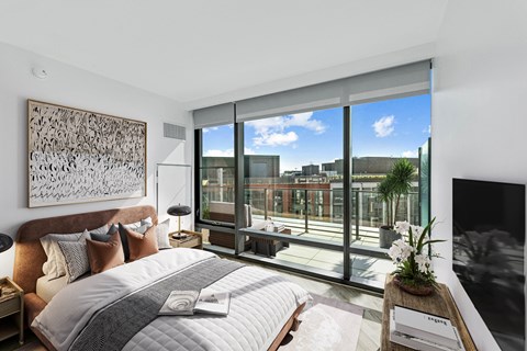 a bedroom with a bed and a large window and a balcony