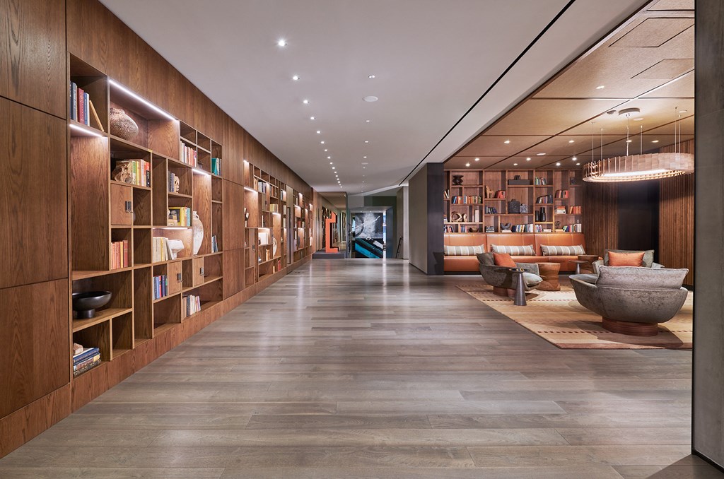 the lobby of a hotel with a long hallway filled with bookshelves and furniture
