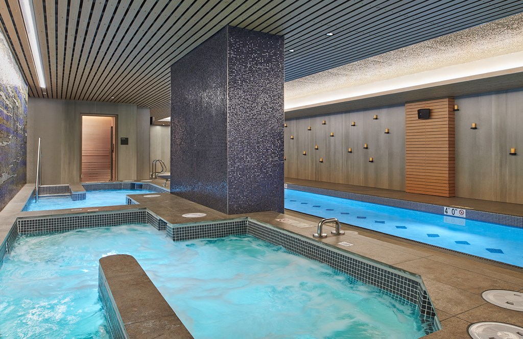 a spa with a large pool of water in a room with wooden doors