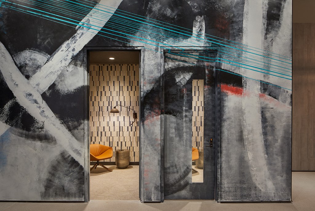 a lobby with two doors and a large painting on the wall