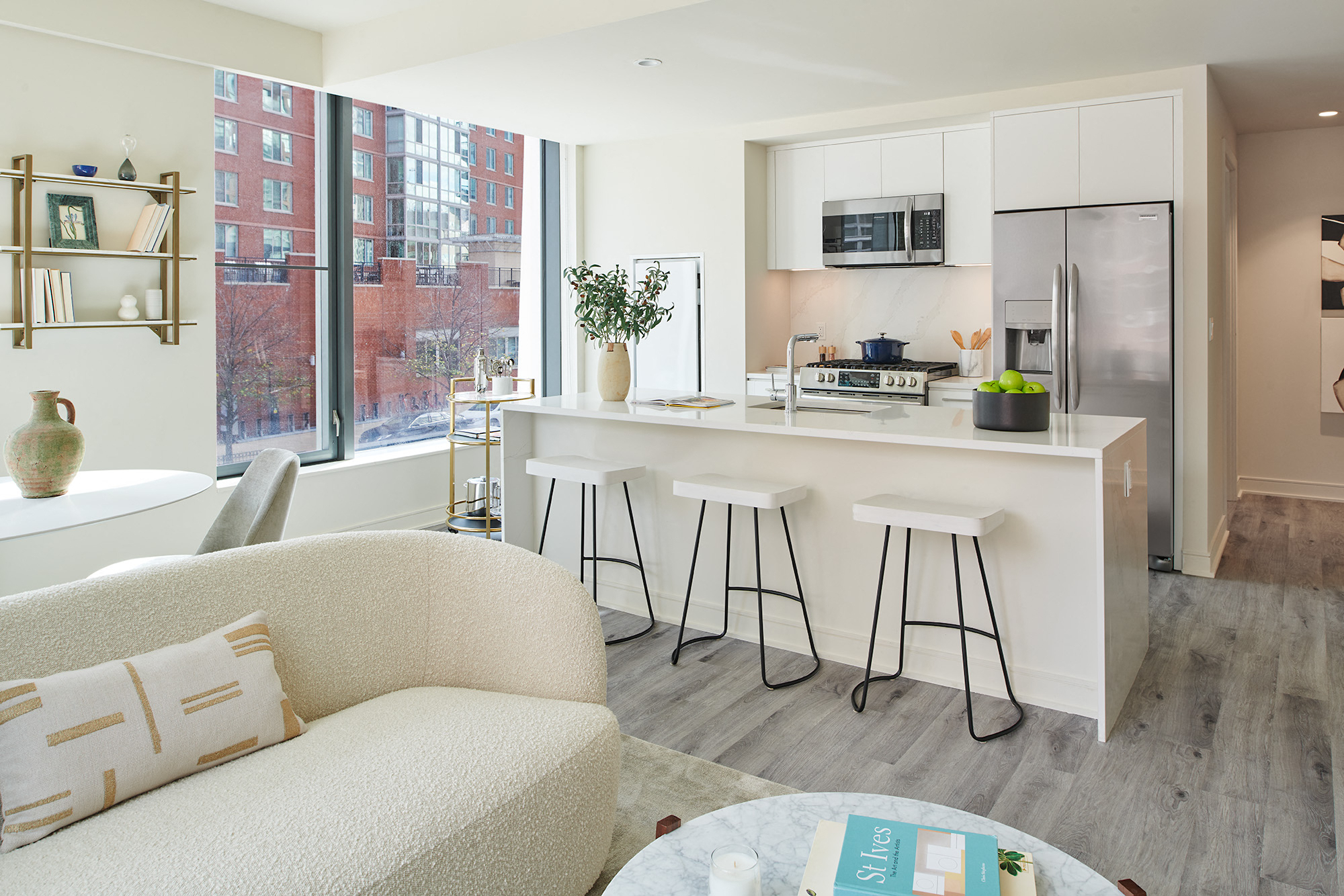 Well lit kitchen with white cabinets and white quarts countertops