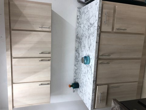 a kitchen with wooden cabinets and a white wall with a door with a blue knob