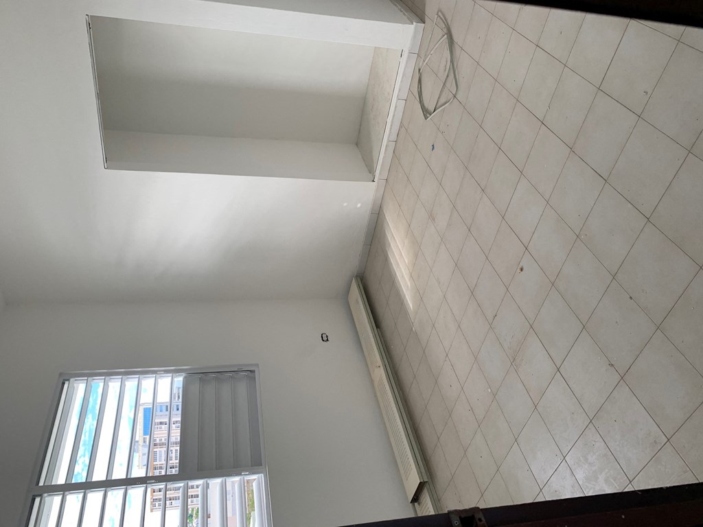 a bathroom with a window and a white tiled wall