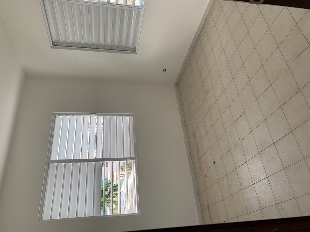 the living room with two windows and a tiled wall