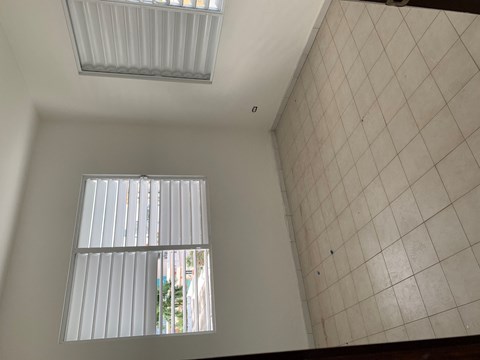 the living room with two windows and a tiled wall