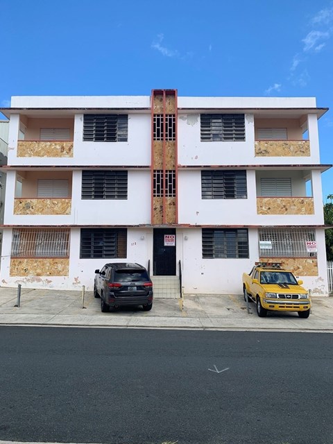 an apartment building with two cars parked in front of it