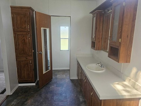 A bathroom with a sink and wooden cabinets.