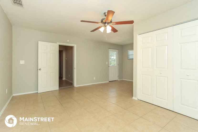 a spacious living room with tile flooring and a ceiling fan