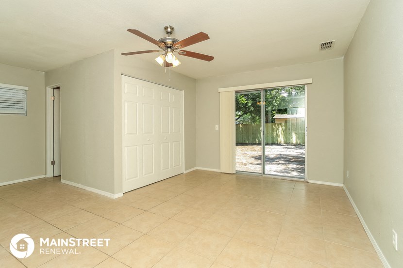 an empty living room with a ceiling fan and a door to a patio
