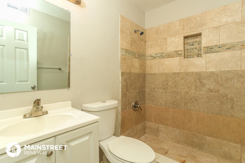 a bathroom with a toilet sink and shower and a mirror