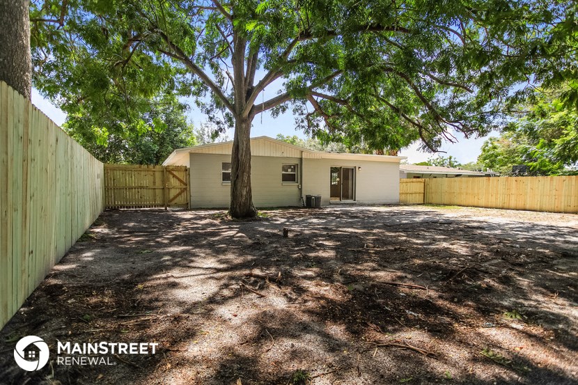 a house with a large tree in the yard and a fence