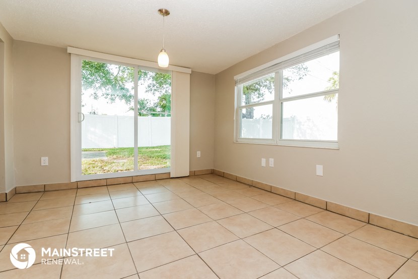 a spacious living room with large windows and tile flooring