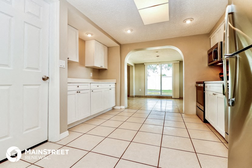 a large kitchen with white cabinets and tiled flooring