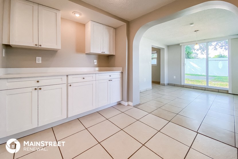 a large kitchen with white cabinets and tiled flooring
