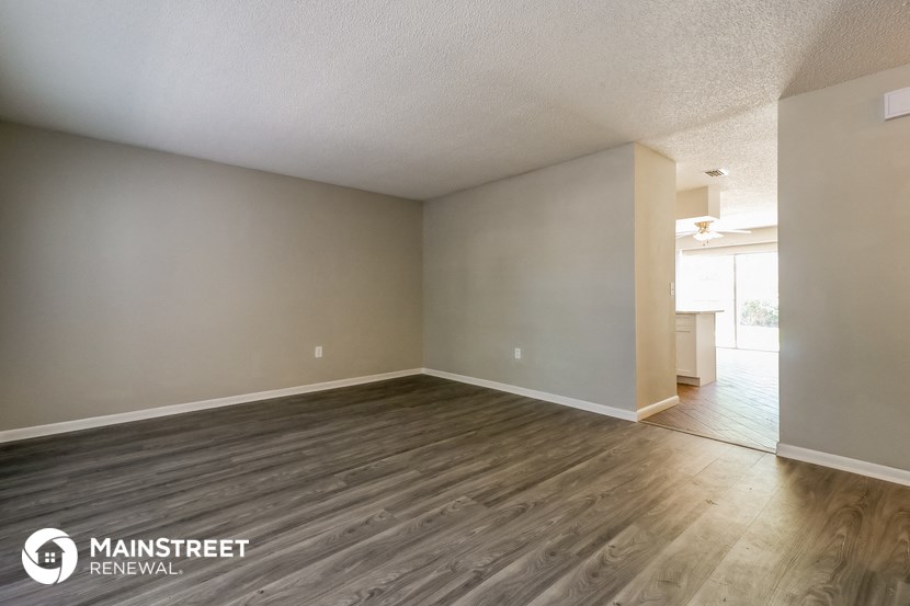 the spacious living room with wood flooring and white walls
