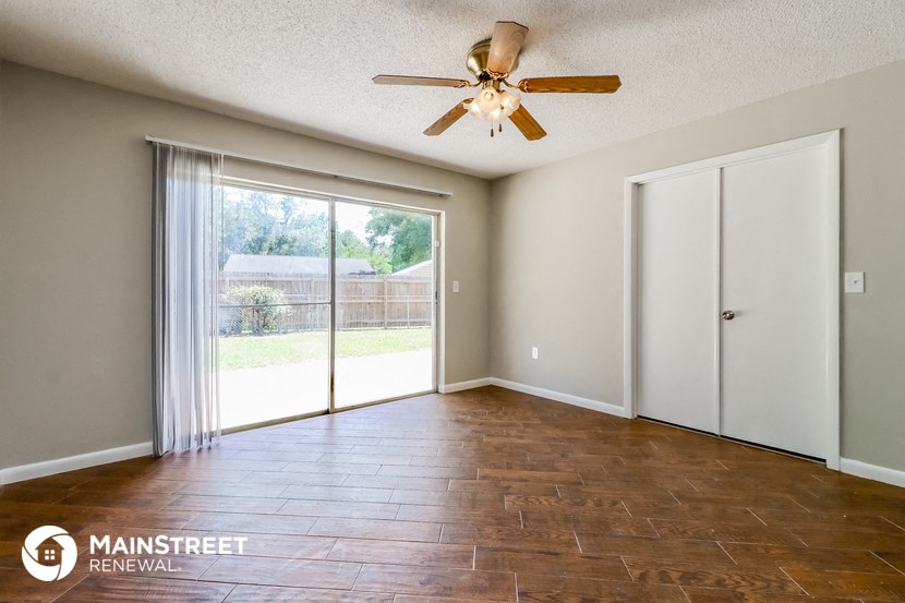 an empty living room with a ceiling fan and a sliding glass door