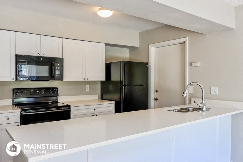 a kitchen with white cabinets and black appliances and a sink