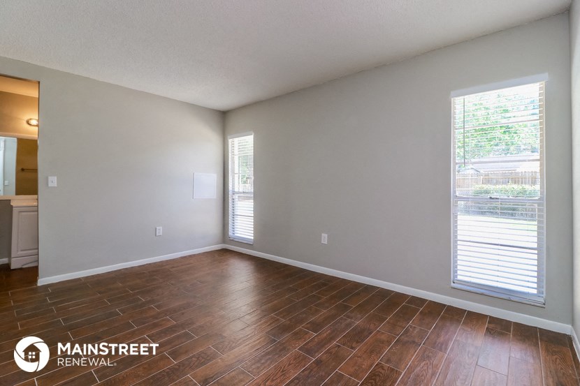the spacious living room with wood flooring and large windows