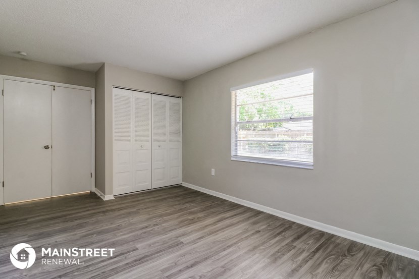 the living room of an apartment with a window and a closet