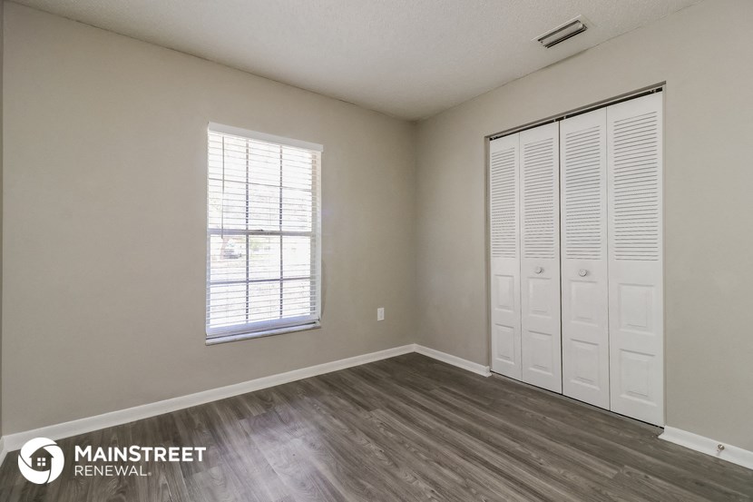 the living room of an apartment with wood flooring and white doors