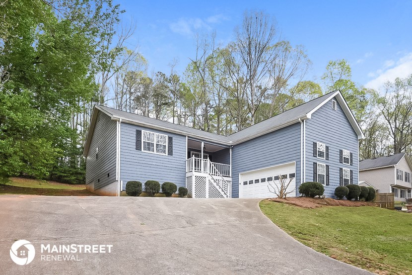 a blue house with a white porch and a driveway