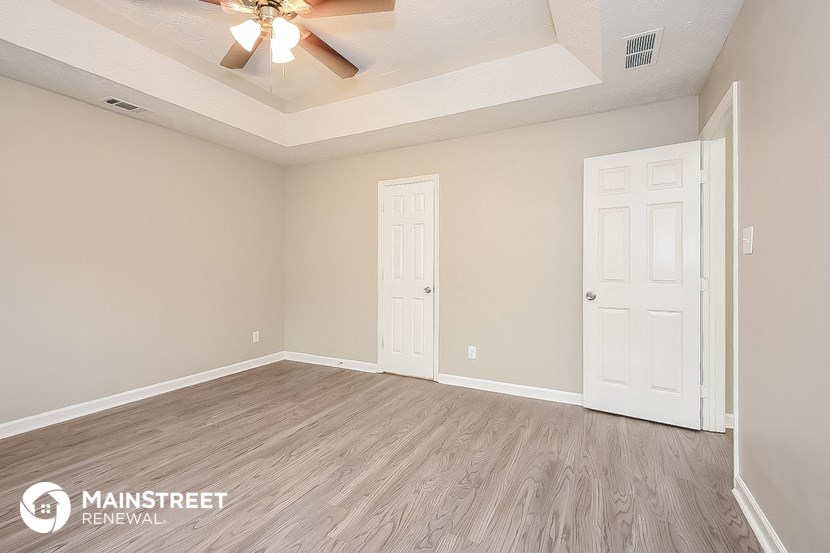 the spacious living room with a ceiling fan and wood flooring