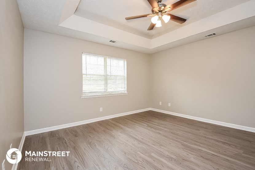 the spacious living room with wood floors and a ceiling fan